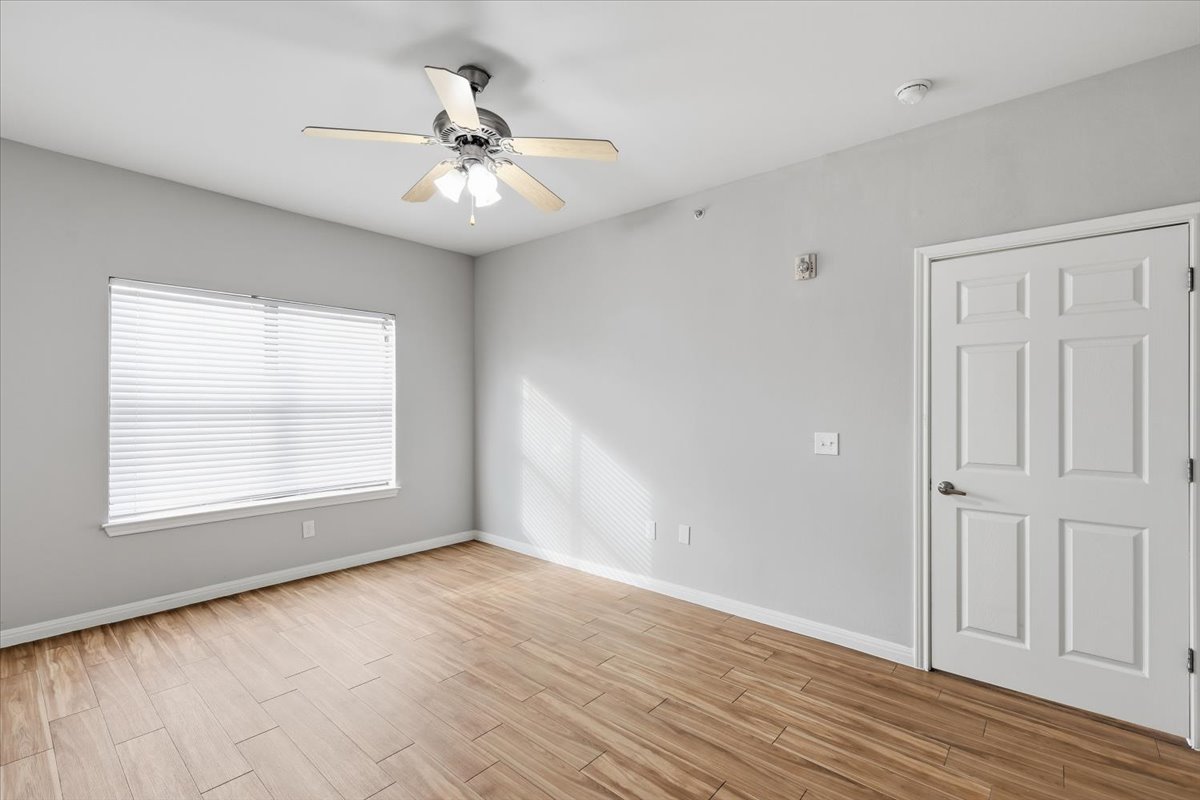 2502 Leon Street, Unit 414 Austin, TX 78705 - Photo 11 of 21 an empty room with wooden floor chandelier fan and windows
