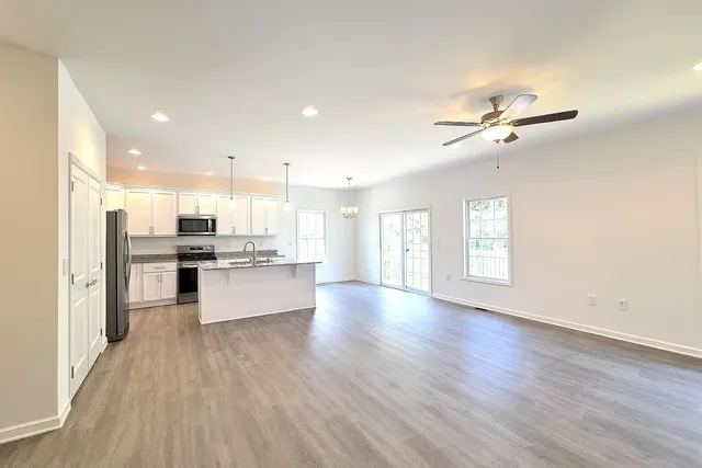 a large kitchen with stainless steel appliances kitchen island a large counter top a sink and a wooden floor