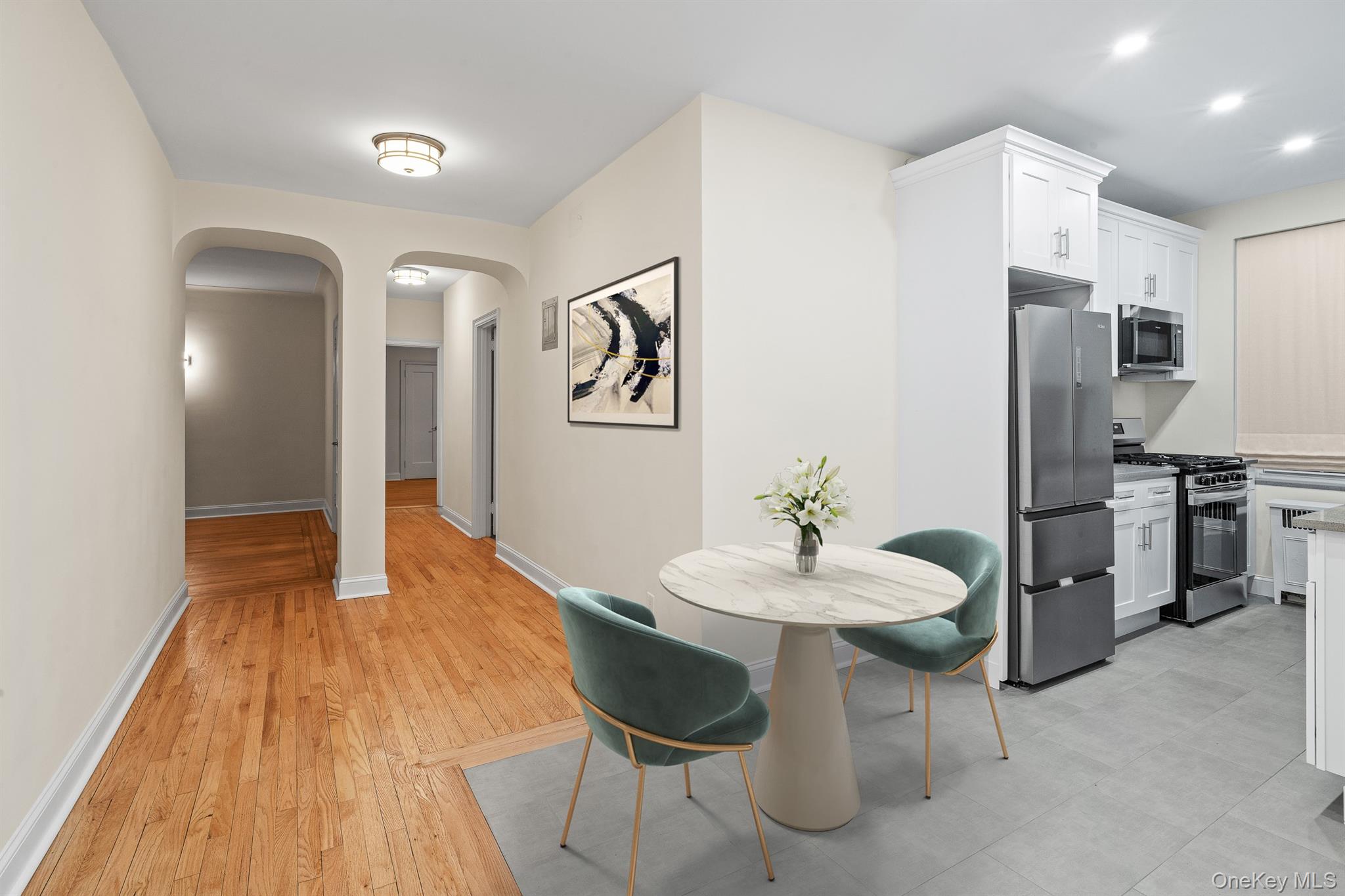 110-07 73rd Road, Unit 2K Queens, NY 11375 - Photo 2 of 17 a kitchen with stainless steel appliances kitchen island granite countertop a refrigerator a stove a microwave oven with white cabinets and wooden floor