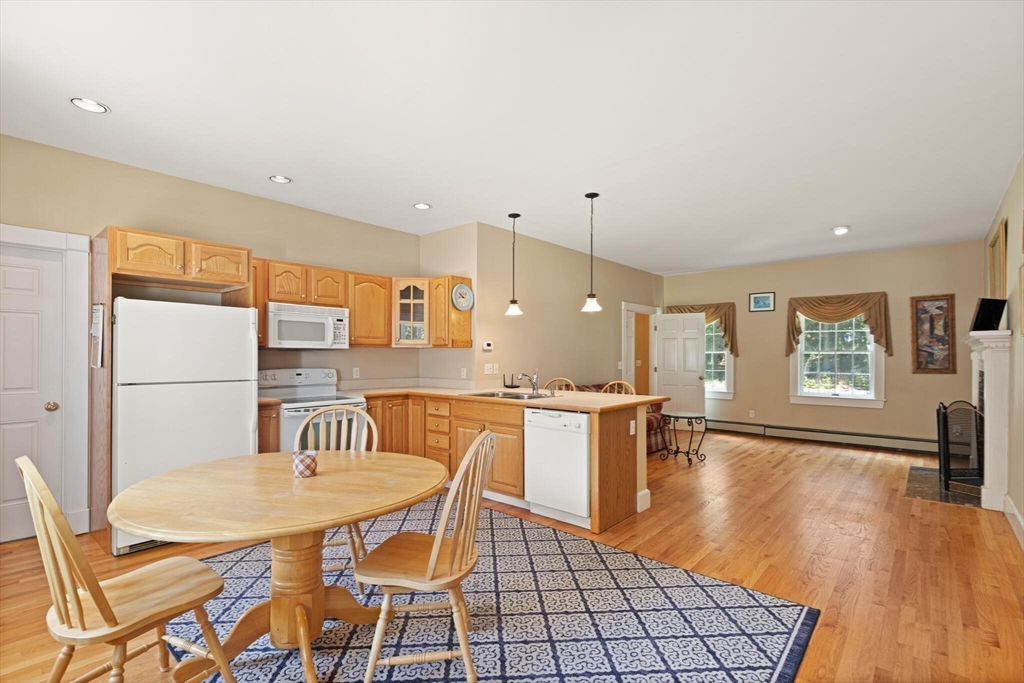 26 Cross Road Boxford, MA 01921 - Photo 31 of 41 a kitchen with stainless steel appliances kitchen island granite countertop a sink a stove a dining table and chairs with wooden floor
