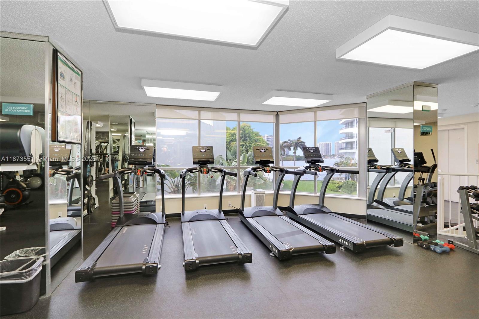3530 Mystic Pointe Drive, Unit 2402 Aventura, FL 33180 - Photo 29 of 33 a room with gym equipment and large mirror