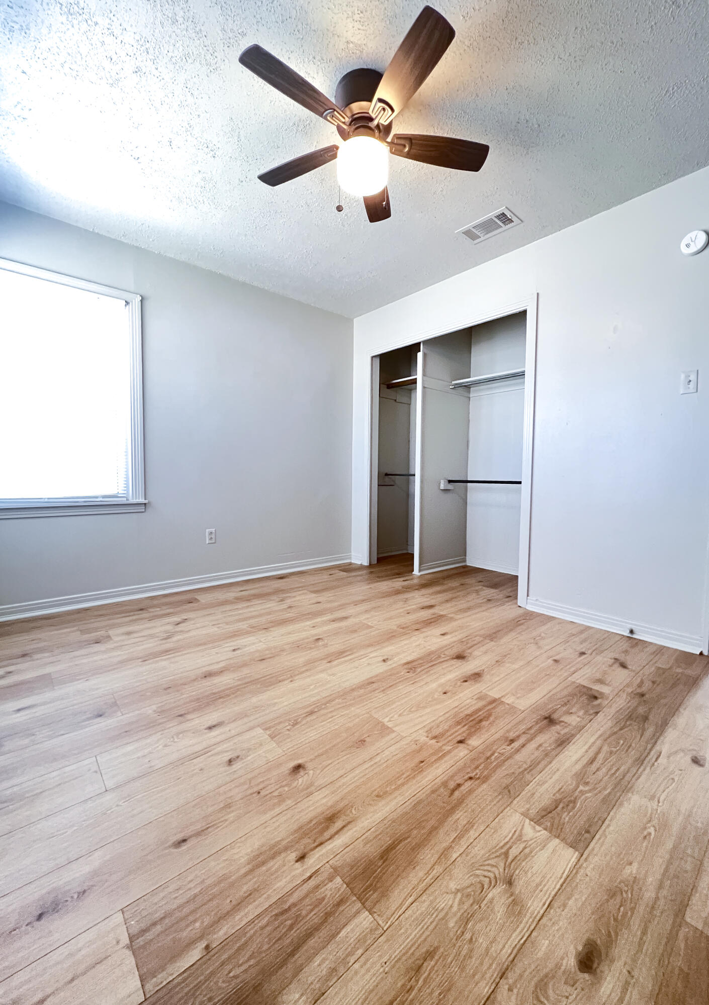 1513 37th Street Lubbock, TX 79412 - Photo 12 of 34 an empty room with wooden floor ceiling fan and windows