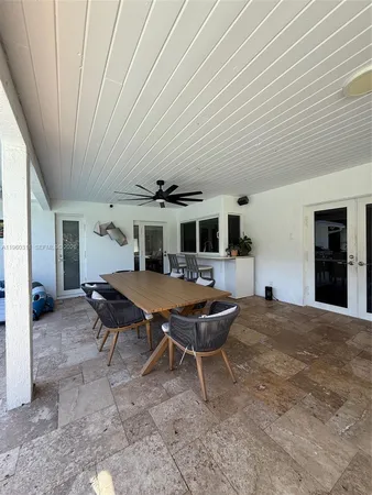a backyard of a house with wooden table and chairs