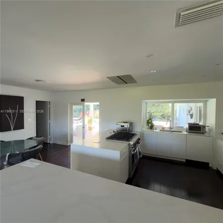 a kitchen with a sink dishwasher a stove top oven a dining table and chairs with wooden floor