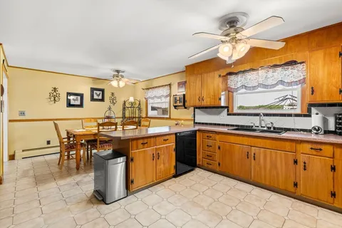 a kitchen with stainless steel appliances granite countertop a sink a stove top oven a dining table and chairs with wooden floor