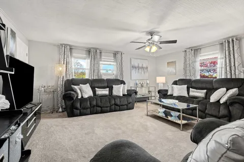 a living room with furniture a ceiling fan and a window