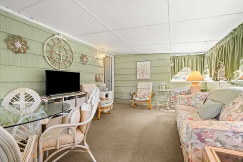 a living room with furniture a flat screen tv and a floor to ceiling window