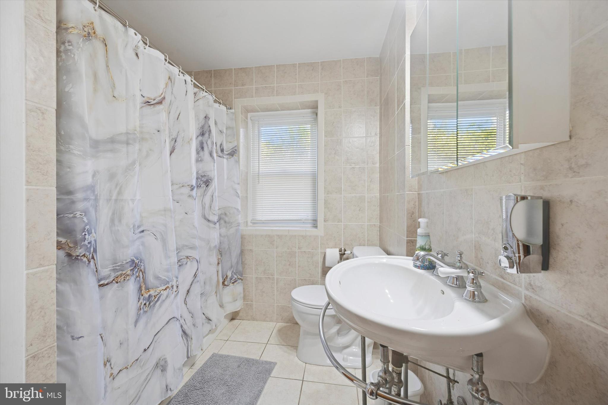 7033 Sherwood Road Philadelphia, PA 19151 - Photo 12 of 16 a bathroom with a sink toilet a mirror and shower