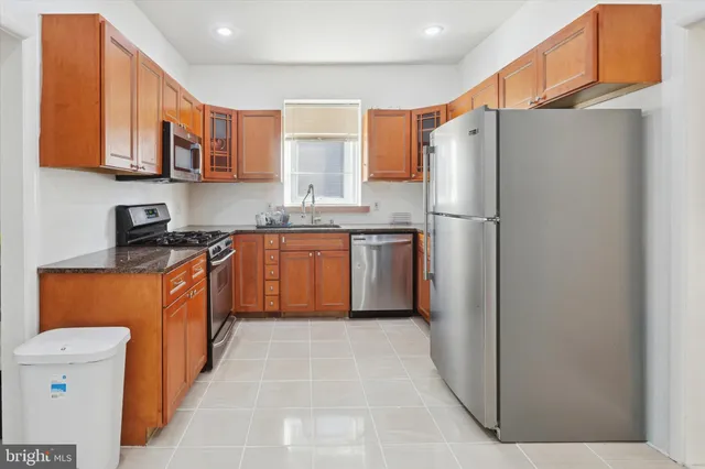 a kitchen with stainless steel appliances granite countertop a refrigerator a sink dishwasher a stove with wooden cabinets