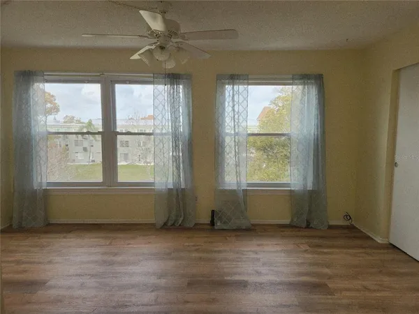 an empty room with wooden floor and windows