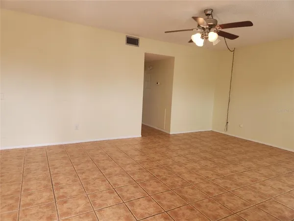 a view of an empty room and chandelier fan