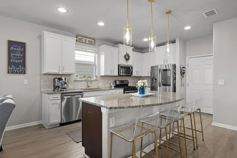 a kitchen with stainless steel appliances white cabinets a stove a microwave and a refrigerator