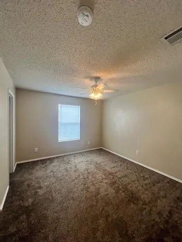 an empty room with windows and fan