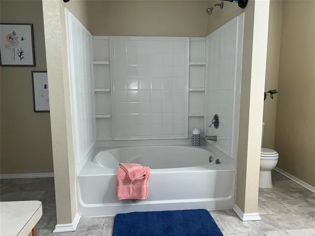 a bathroom with a tub shower and toilet