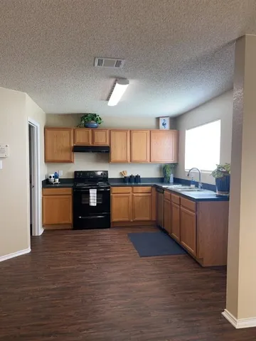 a large kitchen with granite countertop a stove top oven a sink and dishwasher with wooden floor