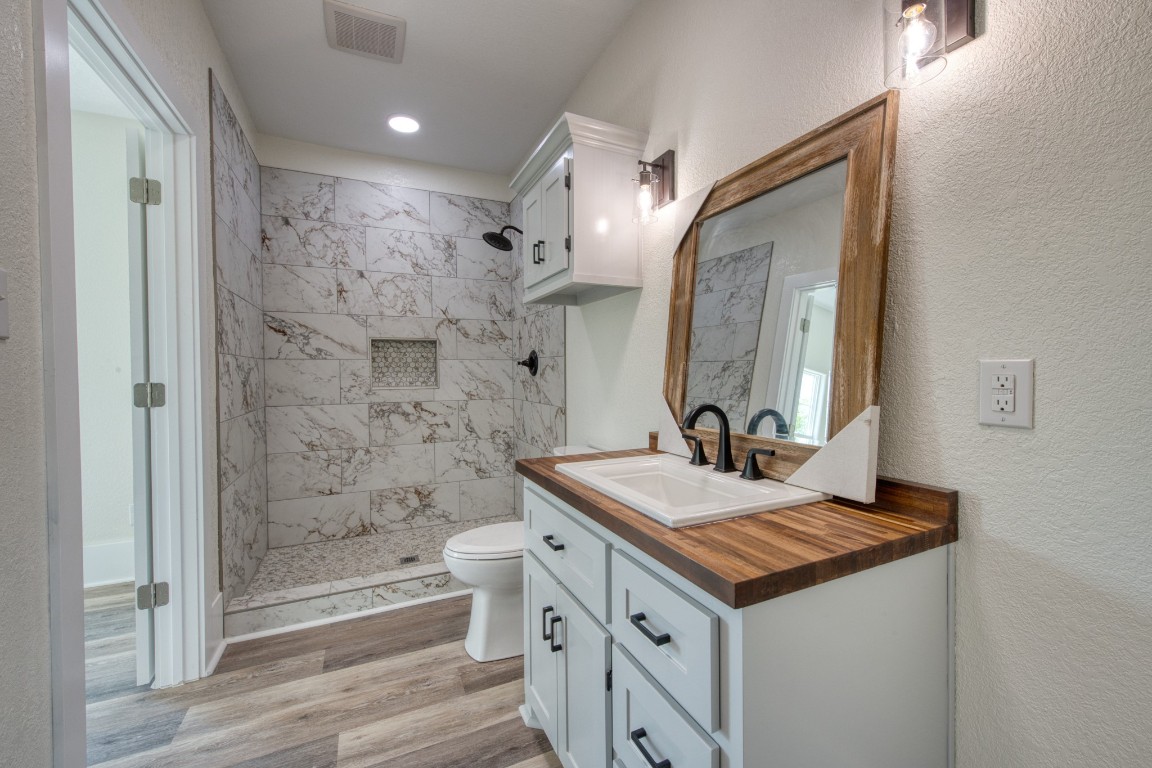 1122 West 2nd Street Freeport, TX 77541 - Photo 15 of 38 a bathroom with a granite countertop sink a toilet a mirror and shower