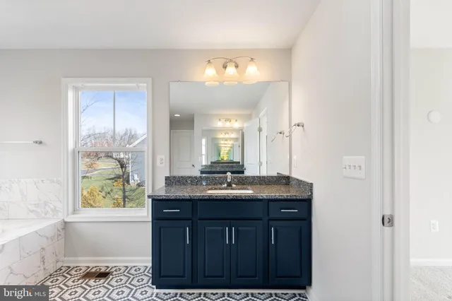 a bathroom with a bathtub shower sink vanity mirror and toilet
