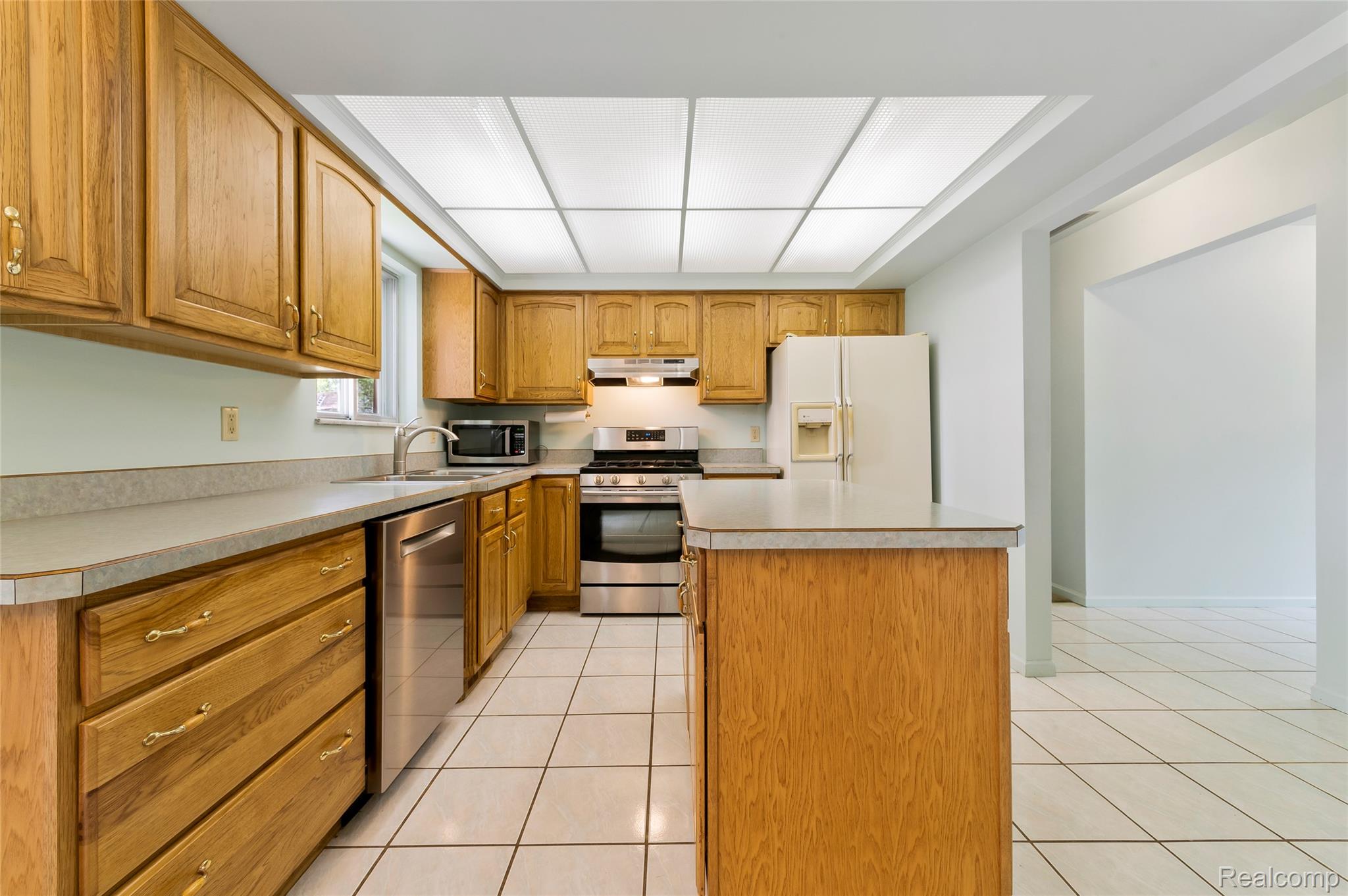 8887 Clark Road Clarkston, MI 48346 - Photo 5 of 40 Kitchen with light tile patterned floors, stainless steel appliances, a kitchen island, and light countertops