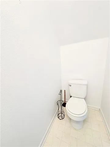 a white toilet sitting next to a white wall