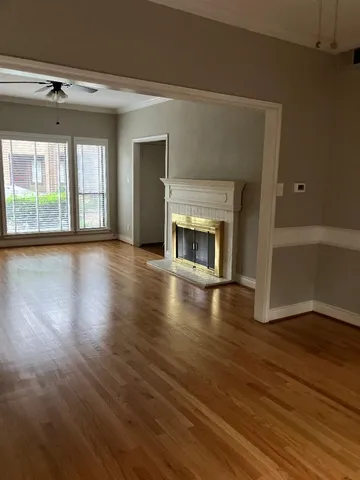 an empty room with wooden floor fireplace and windows