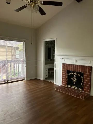 an empty room with wooden floor fireplace and windows