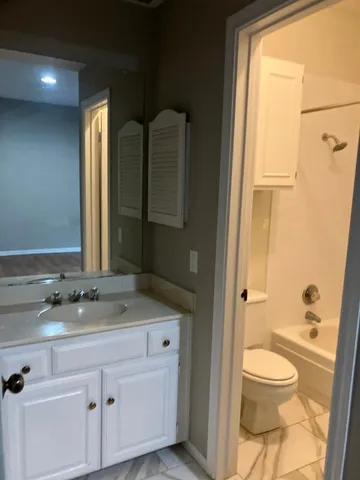 a bathroom with a granite countertop sink toilet a mirror and shower