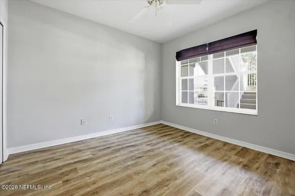 a view of an empty room with wooden floor and a window