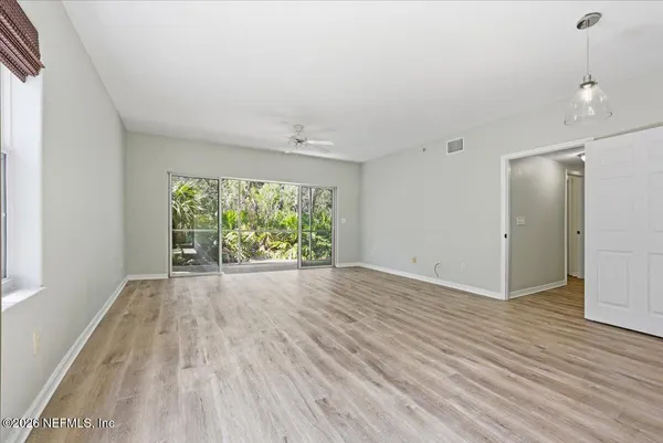 a view of an empty room with wooden floor and a window