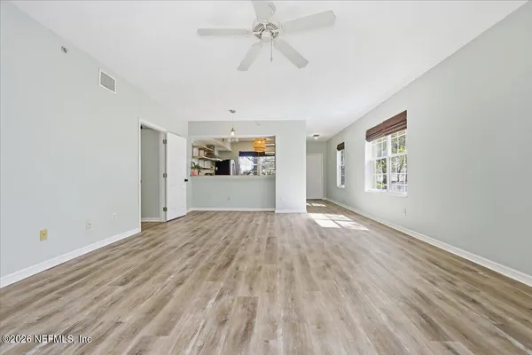 a view of empty room with wooden floor and ceiling fan