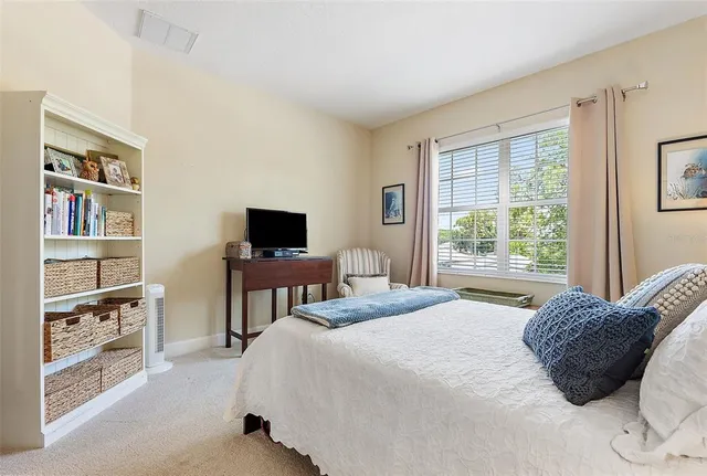 a bedroom with a bed a flat screen tv and a window