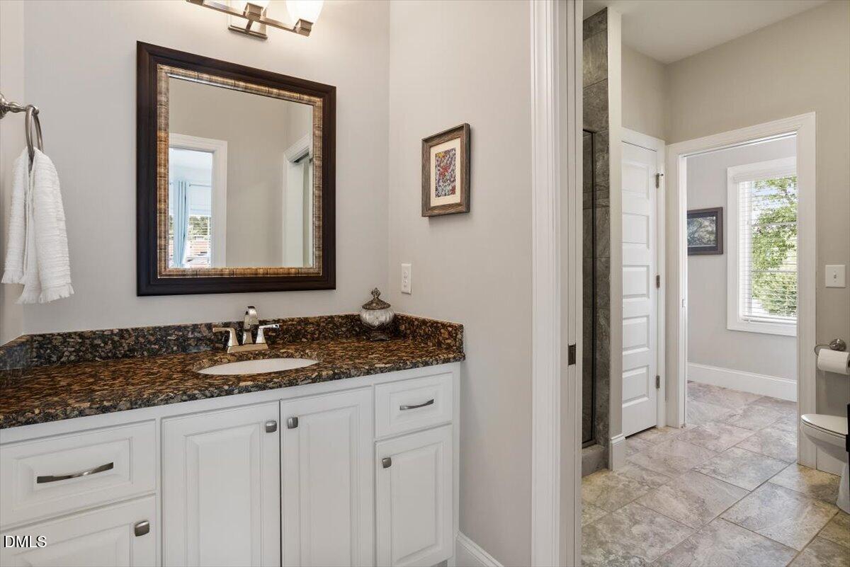 1404 Ivy Lane Raleigh, NC 27609 - Photo 20 of 37 Vanity with a polished granite countertop, undermount sink, and white cabinetry