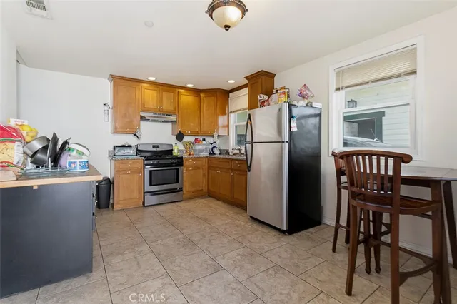 a kitchen with stainless steel appliances granite countertop a stove refrigerator and a dining table