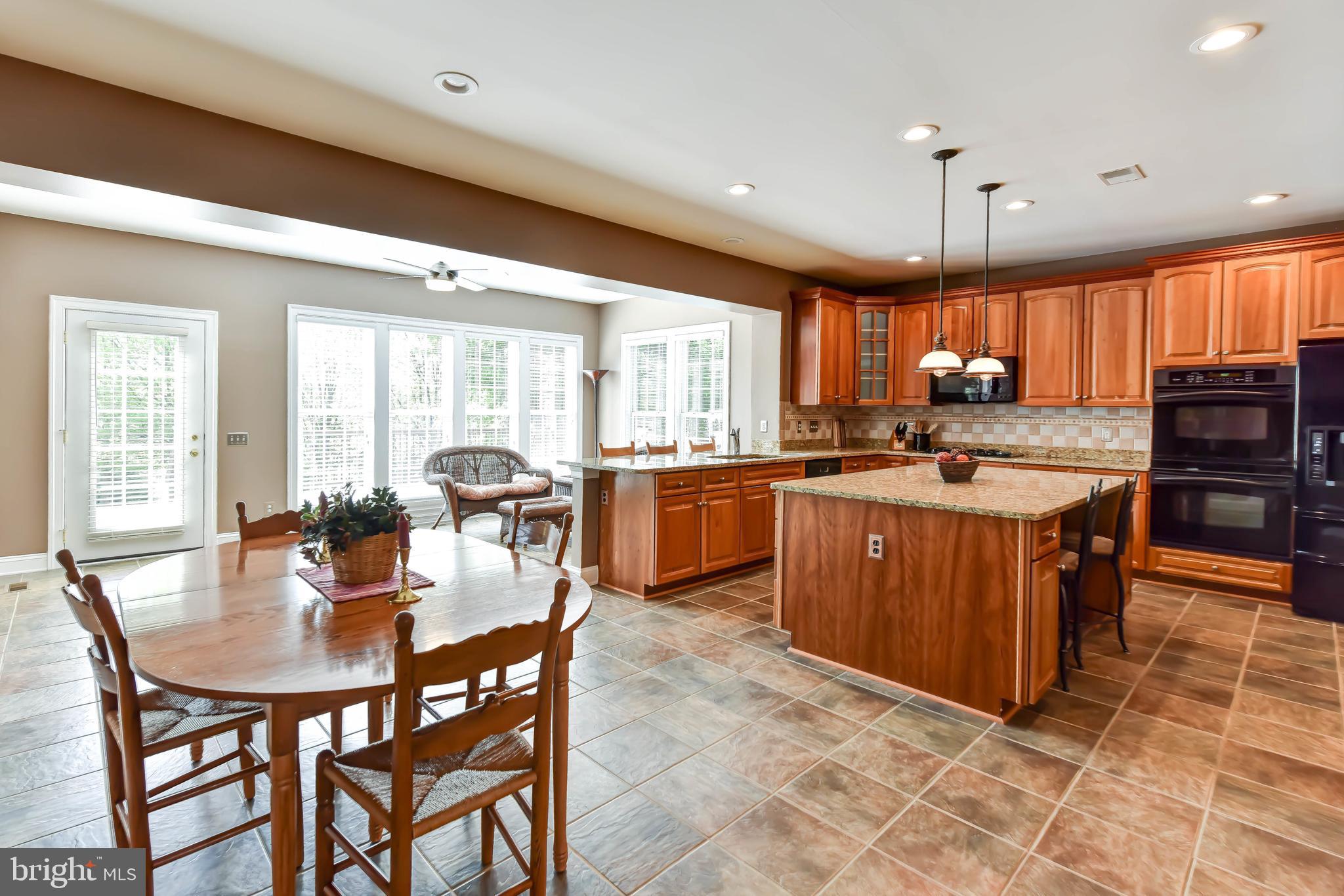 8244 Native Violet Drive Lorton, VA 22079 - Photo 4 of 68 a kitchen with stainless steel appliances granite countertop a stove a sink a microwave a dining table and chairs