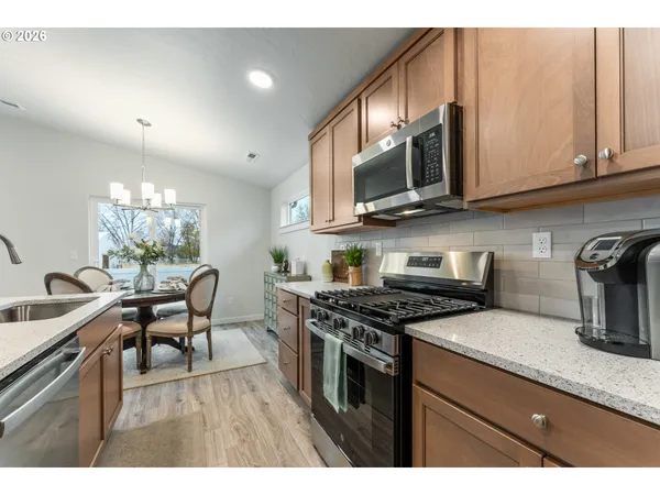 a kitchen with stainless steel appliances granite countertop a stove a sink dishwasher and microwave with wooden floor