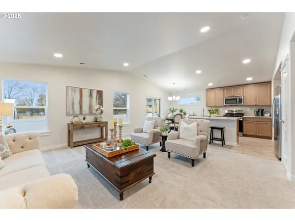 a living room with furniture kitchen view and a large window