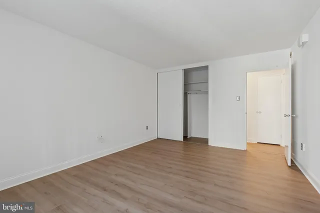 a view of an empty room with wooden floor and closet