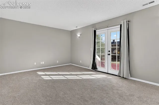a view of an empty room with kitchen and a window