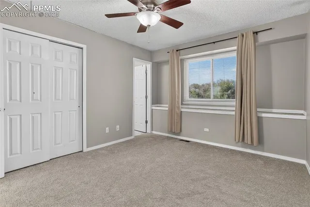 an empty room with closet and a chandelier fan