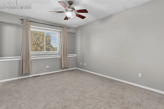 an empty room with a ceiling fan and a window