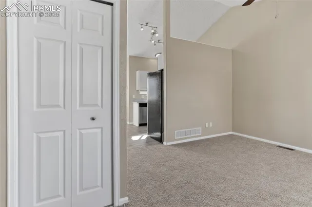 an empty room with a ceiling fan and carpet