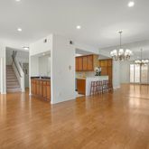 a view of an empty room with kitchen and chandelier
