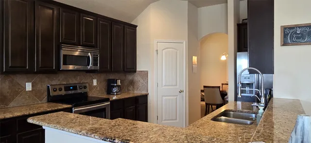 a kitchen with granite countertop wooden cabinets and black appliances