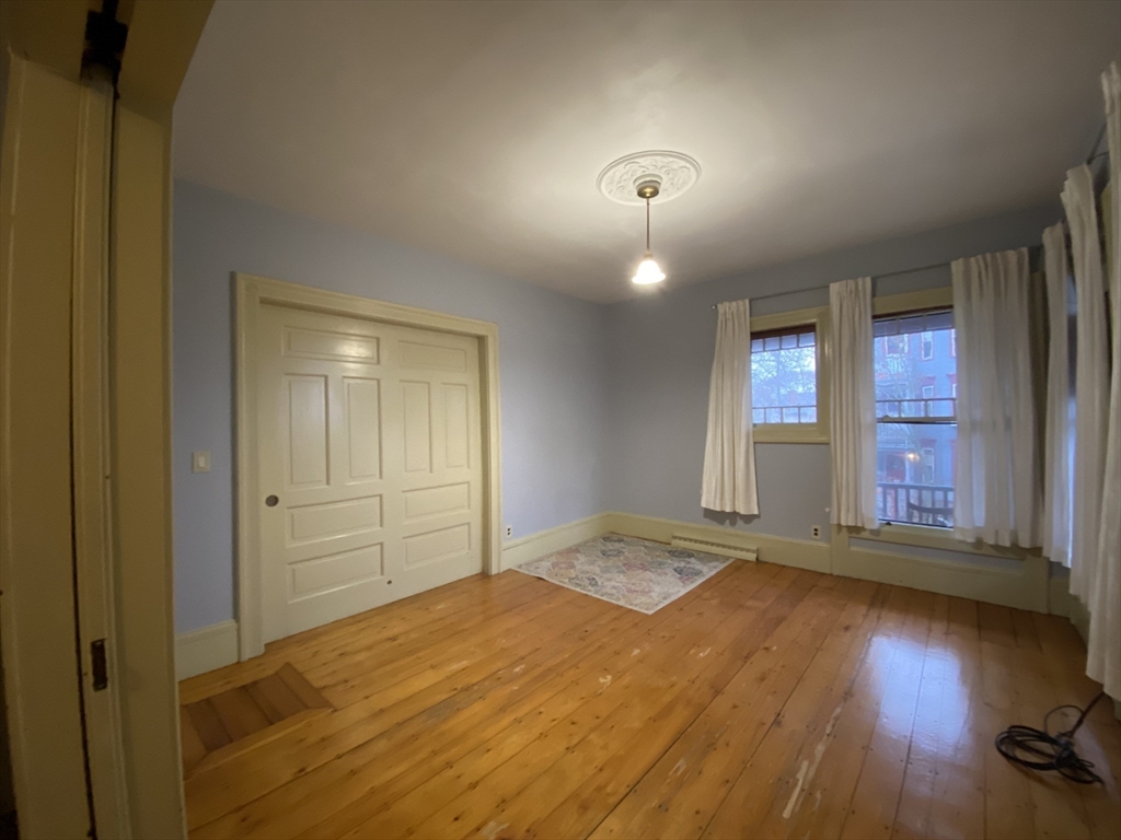 123 Cushing Avenue, Unit 1 Boston, MA 02125 - Photo 8 of 16 an empty room with wooden floor and windows
