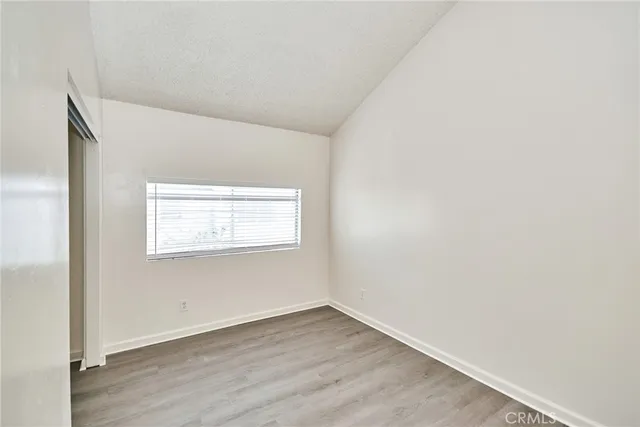 a view of an empty room with wooden floor and closet