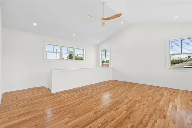 a view of empty room with wooden floor and fan