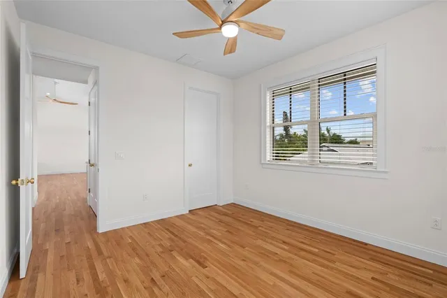 a view of empty room with wooden floor and fan