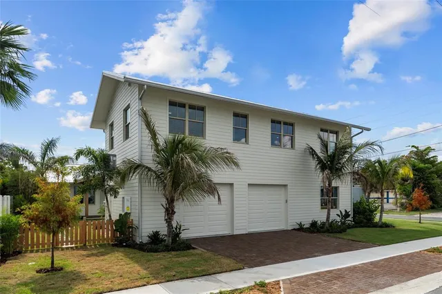 a front view of house with yard along with palm trees