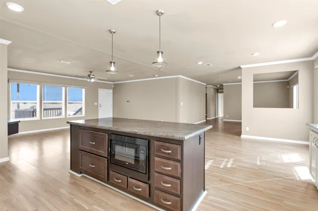 a open kitchen with stainless steel appliances granite countertop a sink a oven and a wooden floors