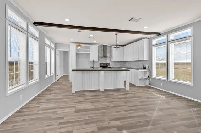 a large white kitchen with granite countertop a large counter top space a sink stainless steel appliances and cabinets