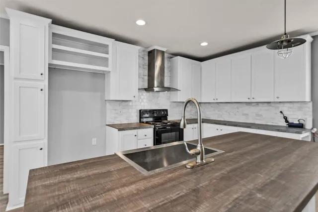 a kitchen with granite countertop a stove and white cabinets